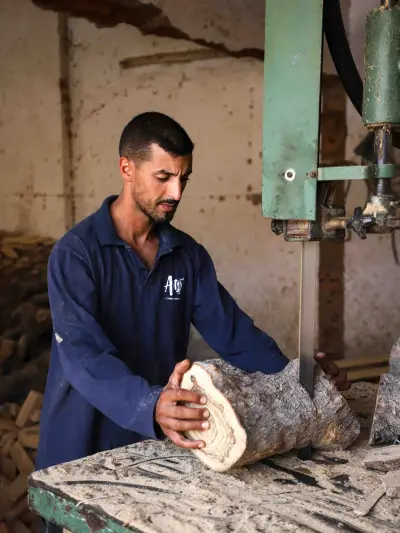 An ArtisRaw artisan turning an olive wood piece on the lathe